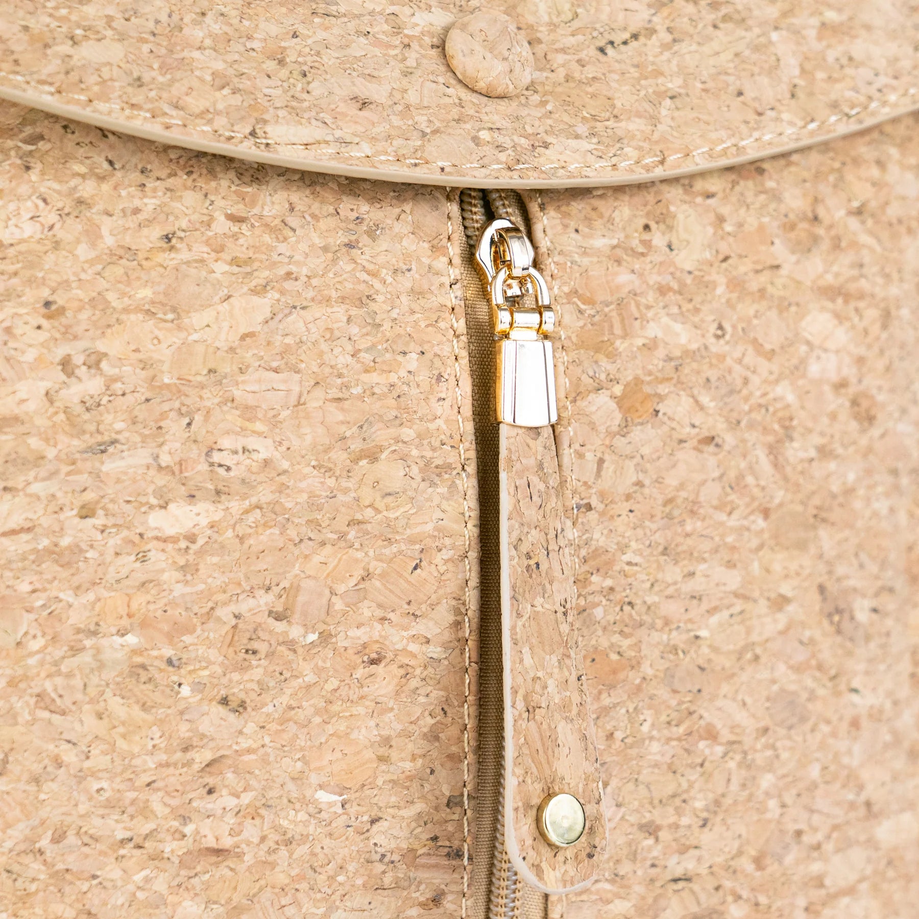 Close-up of gold zipper and cork texture with gold flecks