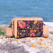 Floral patterned handbag on a rock with water in the background
