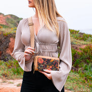 Woman holding a floral-patterned wallet with a natural background