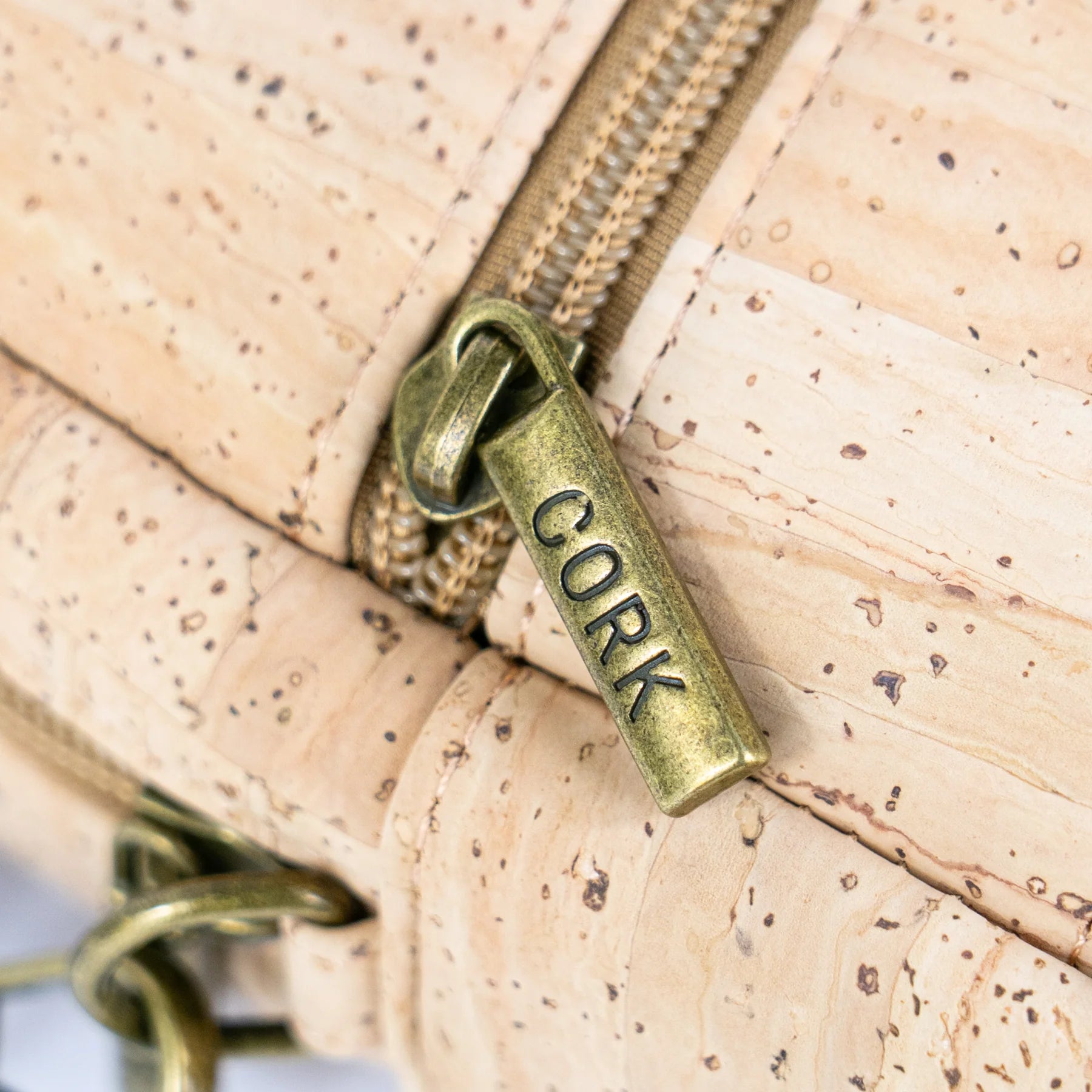 Close-up detail of antique brass zipper pull on cork sling bag