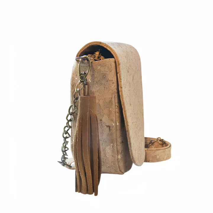 Side view of cork crossbody bag with gold flakes and decorative tassel keychain.