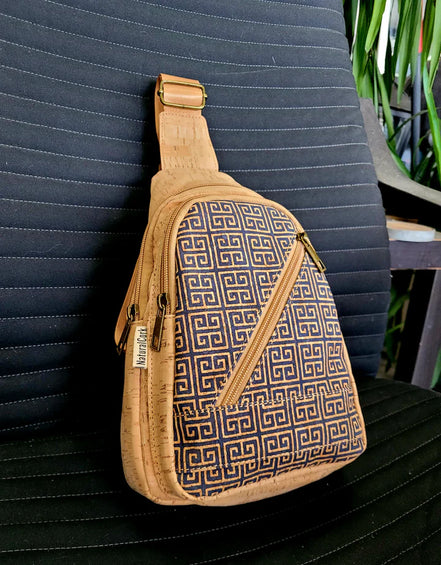 Lifestyle photo of cork sling bag with Greek key print on chair, showing scale and shape.