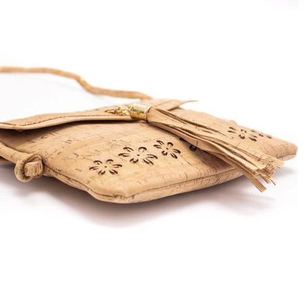 Side-angle view of cork purse with tassel and floral cutouts