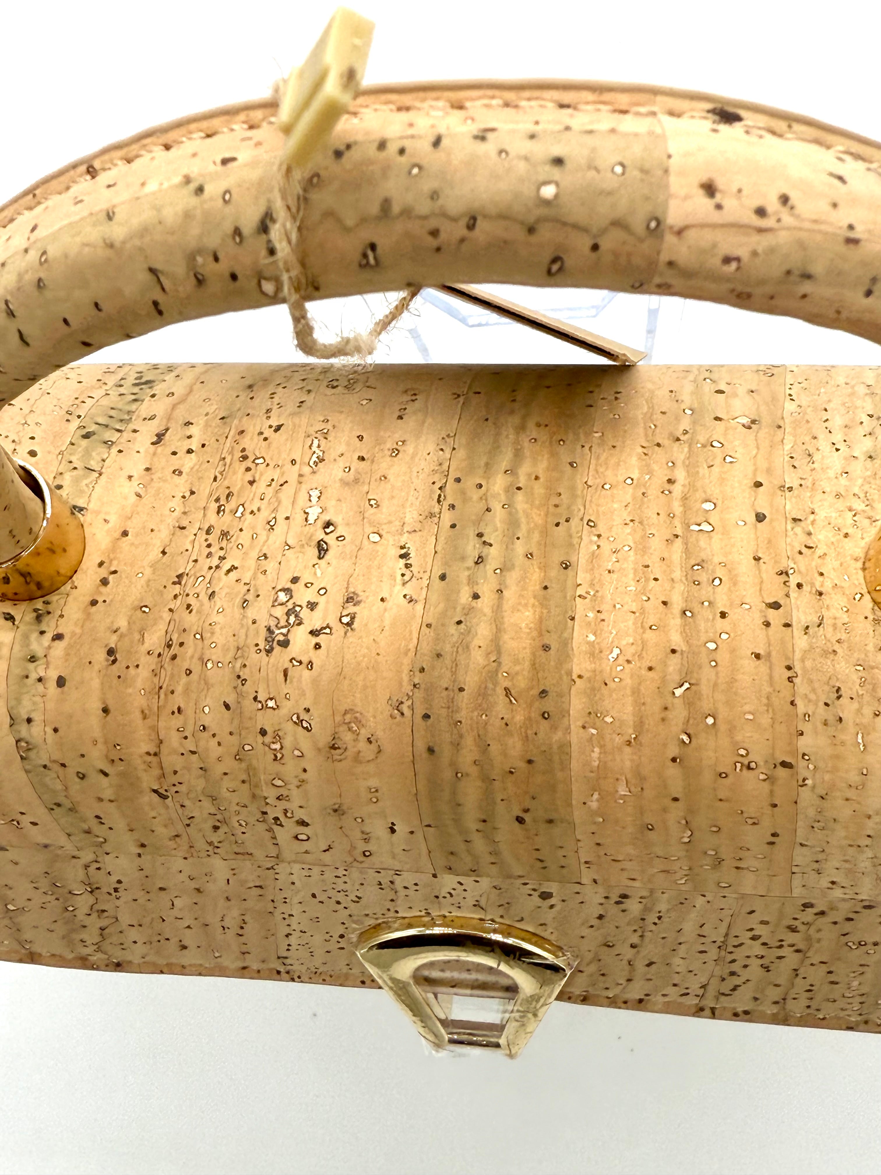 Beige cork handbag with a gold clasp on a white background