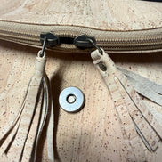 Close up of tassel zippers front of cork crossbody bag