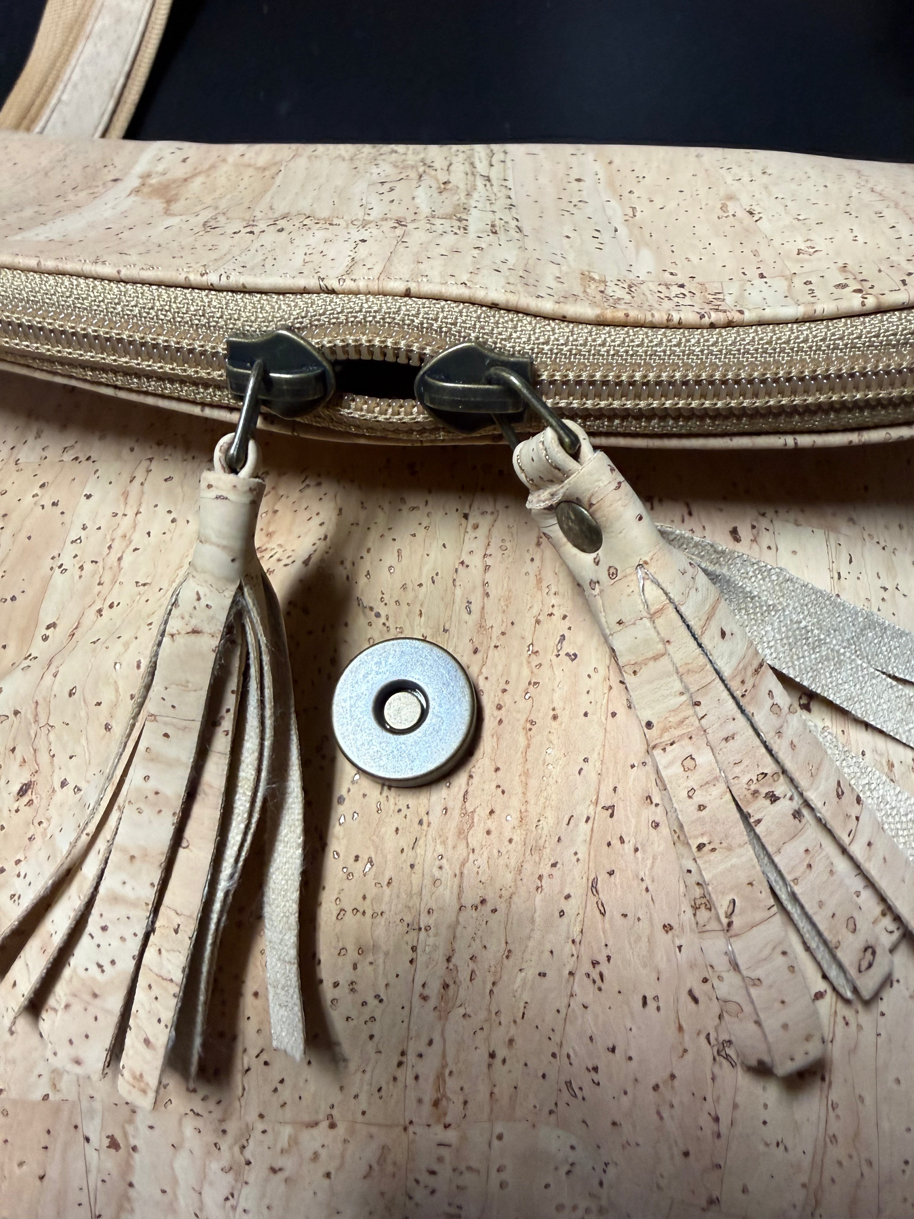 Close up of tassel zippers front of cork crossbody bag