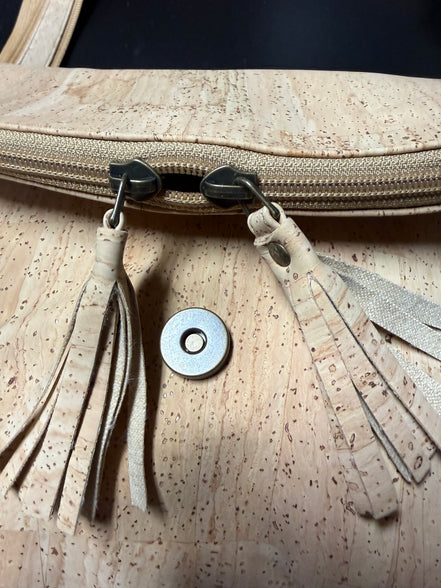 Close up of tassel zippers front of cork crossbody bag