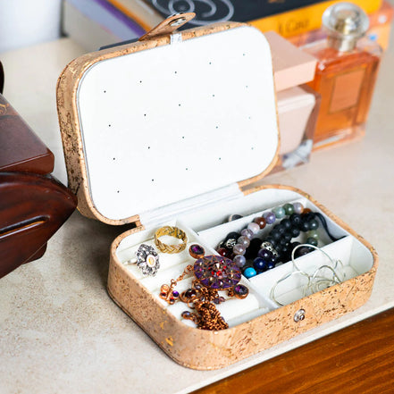 Cork jewelry box open displaying compartments filled with rings and bracelets