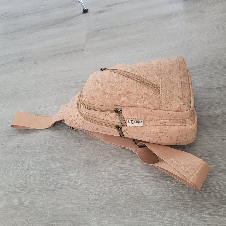 Cork sling bag resting on floor showing curved shape