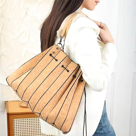Woman wearing pleated cork tote handbag over shoulder with white blazer